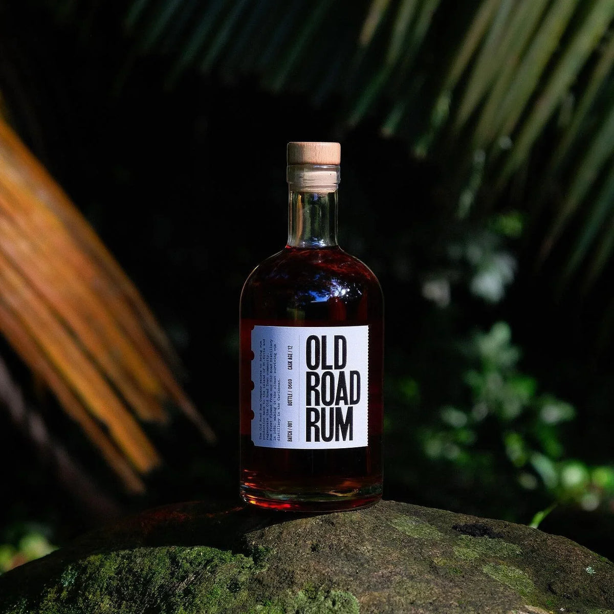 Hands unwrapping a numbered bottle of Old Road Rum 12-year from tissue paper
