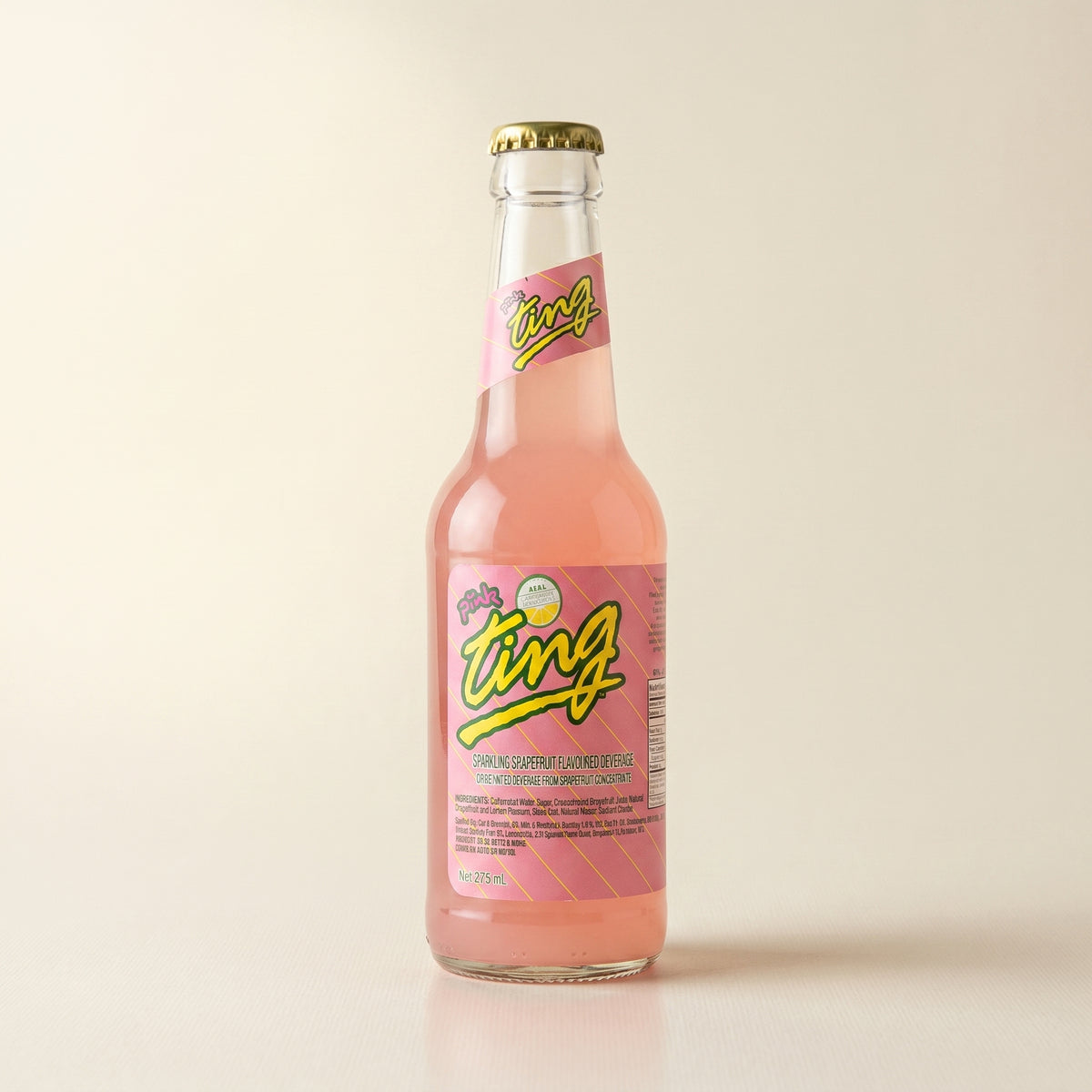 Pink Ting grapefruit soda bottle on a bone studio surface
