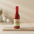 Llewellyn's Guava Pepper Sauce with sliced pink-fleshed guava and red scotch bonnet peppers on a wooden board.